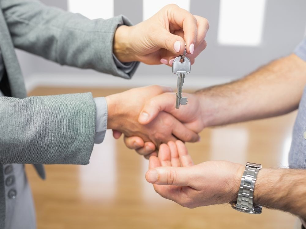 Momento da entrega das chaves de um apartamento comprado na planta sobre a mão do comprador durante assinatura de contrato.