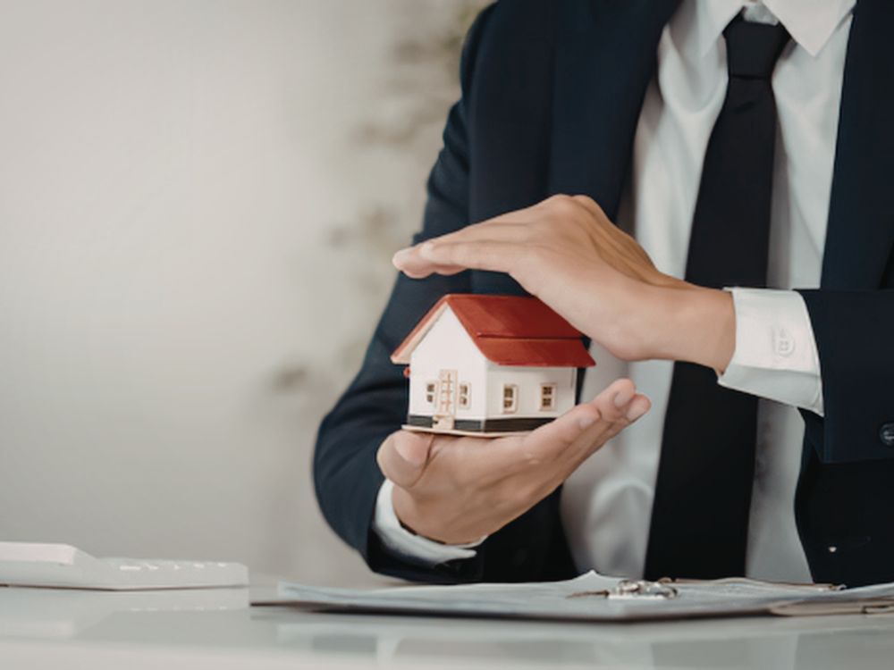Profissional segurando miniatura de casa representando a dúvida se imóvel é ativo ou passivo