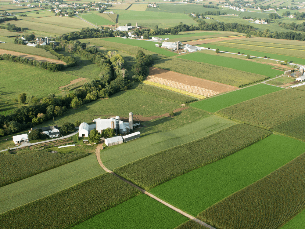 Vista aérea de extensa propriedade rural com plantações, estradas e construções agrícolas, ilustrando quantos alqueires é considerado fazenda