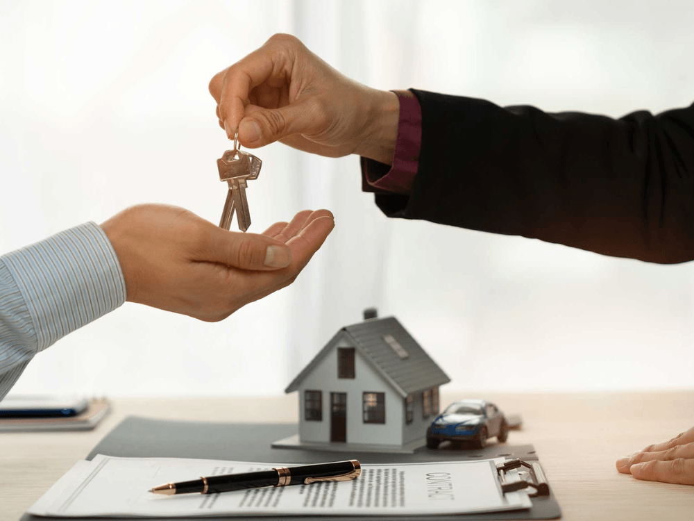 Entrega de chaves entre duas pessoas com contrato e maquete de casa, representando a conclusão da venda após a avaliação do imóvel. Tudo para explicar como avaliar um imóvel para vender