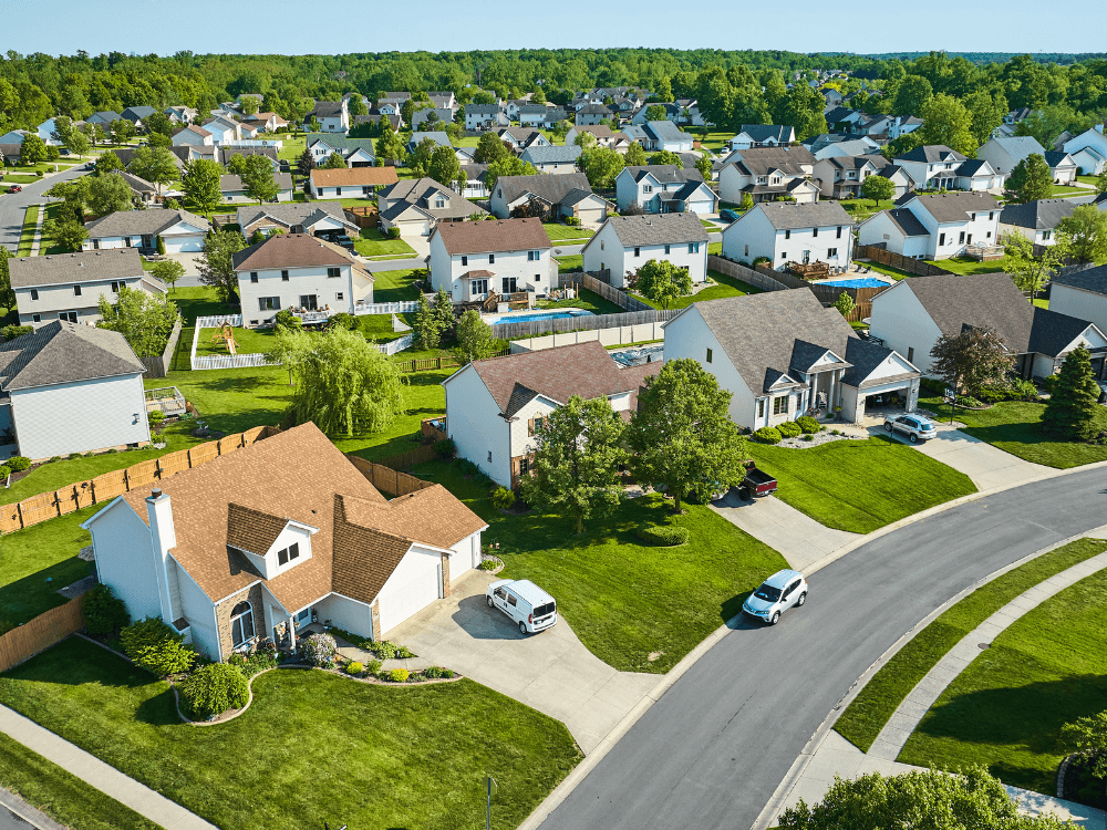 Vista aérea de bairro residencial com casas, ruas pavimentadas, jardins e áreas verdes, representando opções de imóveis antigos.