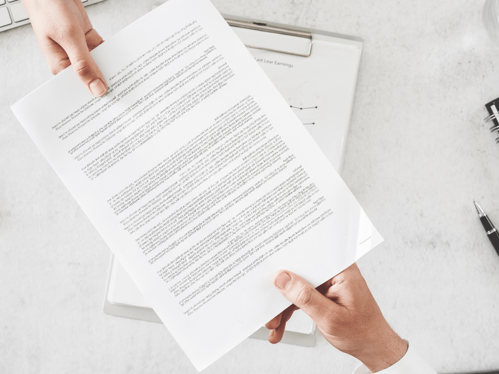 Pessoa segura um documento imobiliário para análise, destacando a importância da documentação na compra de um imóvel.