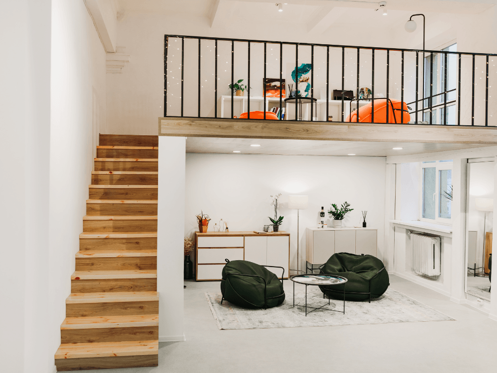 Apartamento duplex com escada de madeira, sala de estar no piso inferior e área elevada com guarda-corpo preto