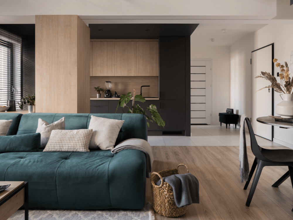 Sala de estar com sofá azul integrada à cozinha planejada em um ambiente residencial de dois níveis
