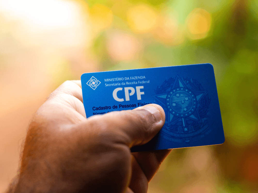 Mão segura um cartão azul com a identificação do CPF da Receita Federal, documento utilizado na identificação cadastral para alugar um imóvel.